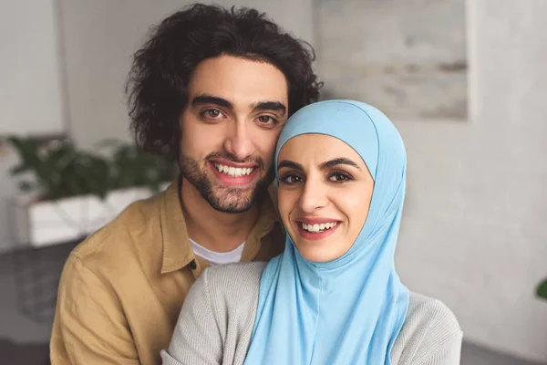 Porträt eines lächelnden muslimischen Paares, das zu Hause in die Kamera schaut — Stockfoto