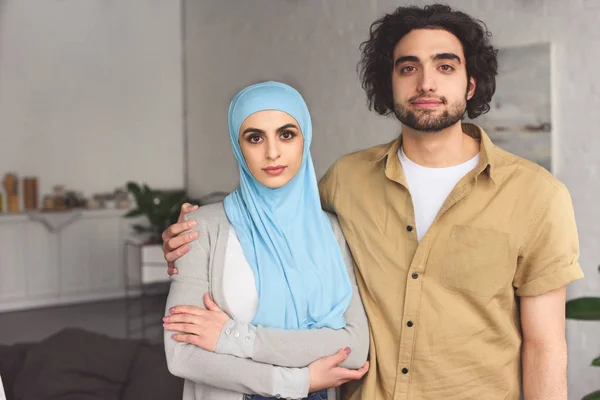 Cariñosa pareja musulmana mirando a la cámara en casa - foto de stock
