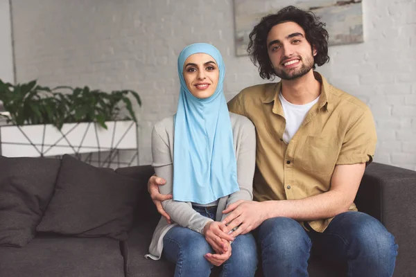 Lächelndes muslimisches Paar, das sich umarmt und zu Hause in die Kamera schaut — Stockfoto