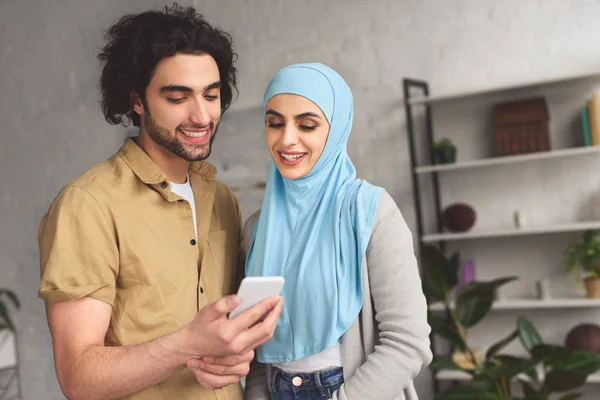 Muslim couple looking at smartphone at home — Stock Photo