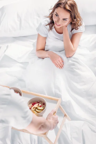 Partial view of man brought breakfast in bed for smiling girlfriend — Stock Photo
