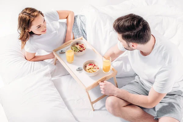 Высокий угол зрения молодой пары, завтракающей в постели утром вместе — стоковое фото