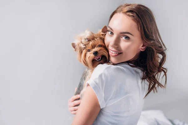 Portrait of young smiling woman with yorkshire terrier looking at camera isolated on grey — Stock Photo