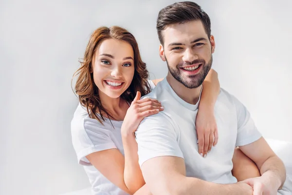 Portrait of smiling pretty woman hugging boyfriend isolated on grey — Stock Photo