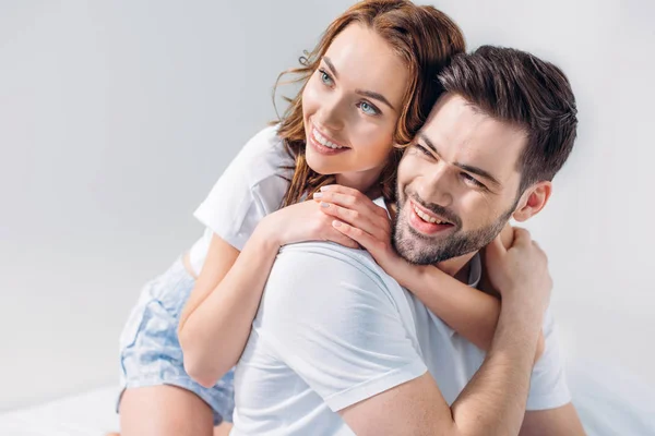 Portrait of young pretty woman hugging boyfriend isolated on grey — Stock Photo