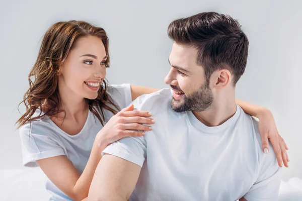 Portrait of young pretty woman hugging boyfriend isolated on grey — Stock Photo