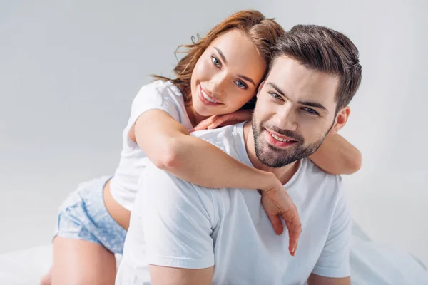 Portrait of young pretty woman hugging boyfriend isolated on grey — Stock Photo