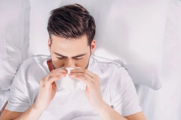 Overhead view of man having running nose and resting in bed — Stock Photo