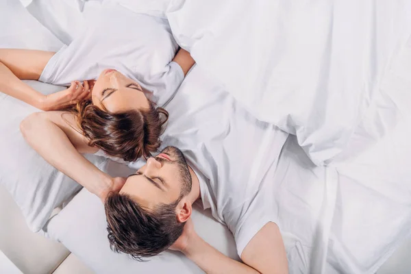 Vista aérea de pareja joven durmiendo en la cama juntos - foto de stock