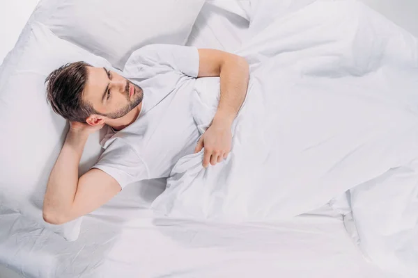 Vue aérienne de l'homme barbu coûteux regardant loin tout en se reposant dans le lit — Photo de stock