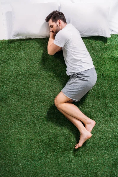 Vue aérienne du jeune homme dormant sur des oreillers sur une pelouse verte — Photo de stock