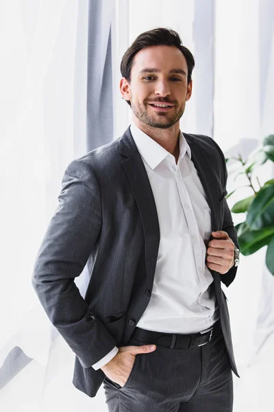Smiling handsome businessman looking at camera in office — Stock Photo
