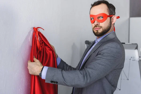 Super businessman wearing mask and cape in office — Stock Photo