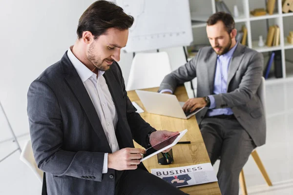 Beaux hommes d'affaires travaillant avec ordinateur portable et tablette au bureau — Photo de stock