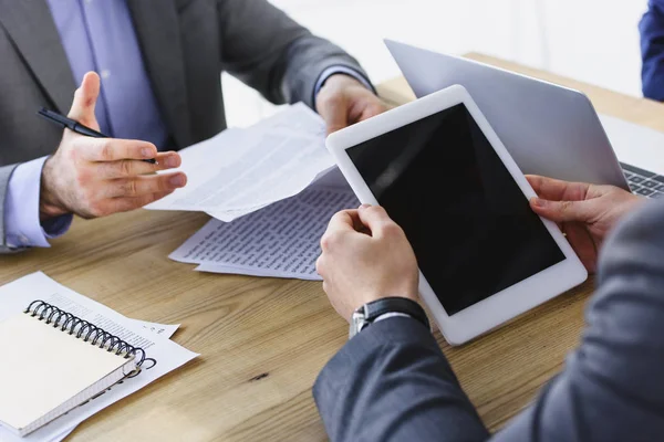 Обрезанный имидж бизнесменов, держащих планшеты и документы в офисе — стоковое фото