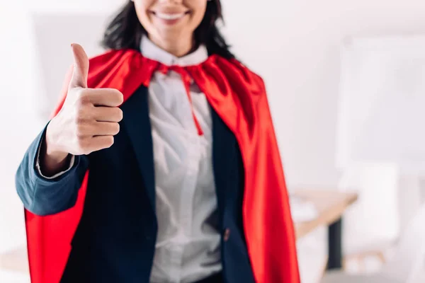 Abgeschnittenes Bild einer Superunternehmerin im Umhang, die im Büro den Daumen nach oben zeigt — Stockfoto