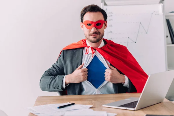 Schöner Superunternehmer in Maske und Umhang mit blauem Hemd im Büro — Stockfoto