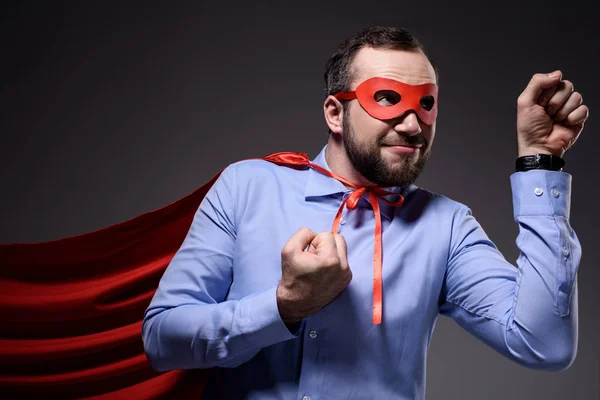 Sonriente guapo super hombre de negocios en máscara y capa mostrando puños aislados en negro - foto de stock