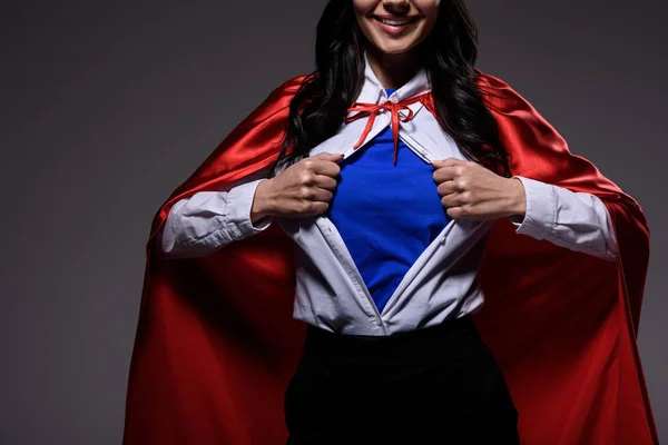 Cropped image of super businesswoman in red cape showing blue shirt isolated on black — Stock Photo