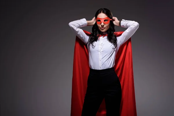 Atractiva super mujer de negocios en capa roja máscara de atar aislado en negro — Stock Photo