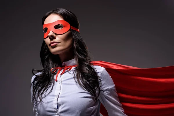 Attractive super businesswoman in red cape and mask isolated on black — Stock Photo