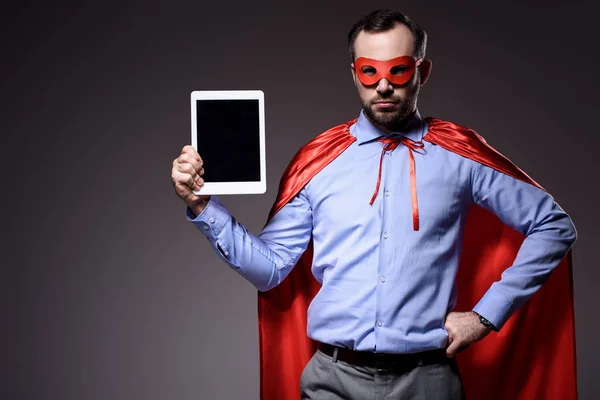 Guapo super hombre de negocios en la máscara y la capa de la celebración de la tableta aislado en negro - foto de stock