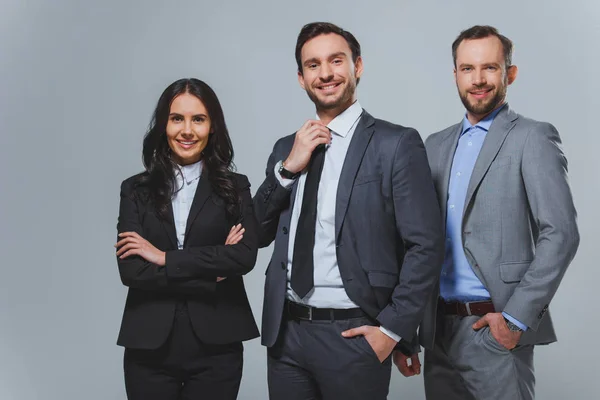 Sonrientes colegas de negocios mirando a la cámara aislada en gris — Stock Photo