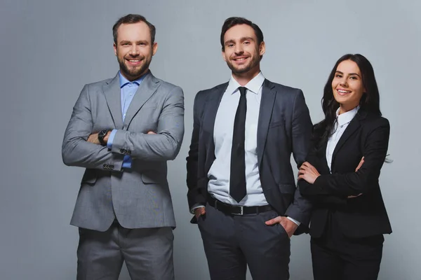 Sonrientes empresarios mirando a la cámara aislada en gris - foto de stock