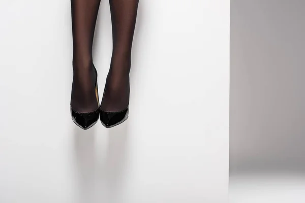 Gambe femminili in collant nero e scarpe su sfondo bianco — Foto stock