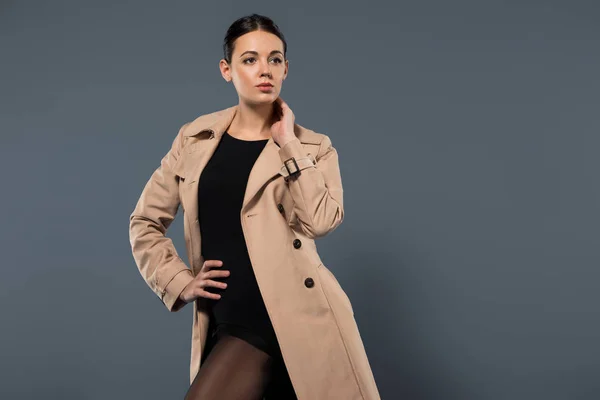 Giovane donna che indossa trincea beige posa isolata su sfondo scuro — Foto stock