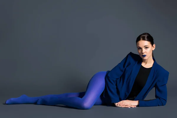 Chica en ropa azul acostado sobre fondo oscuro - foto de stock
