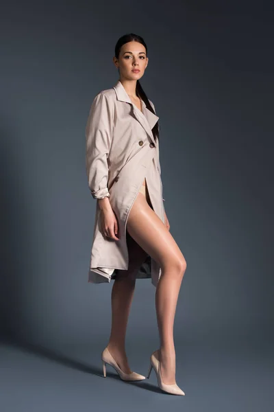 Young woman wearing beige trench posing on dark background — Stock Photo