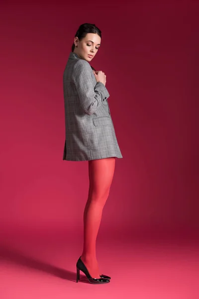 Женщина с тонкими ногами в красных нейлоновых колготках на красном фоне — стоковое фото