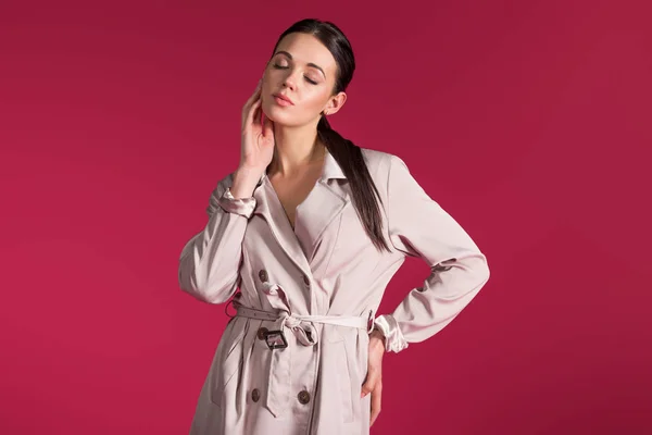 Young woman wearing beige trench posing isolated on red background — Stock Photo