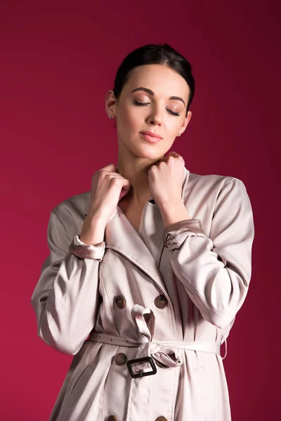 Dreamy girl wearing beige trench isolated on red background — Stock Photo