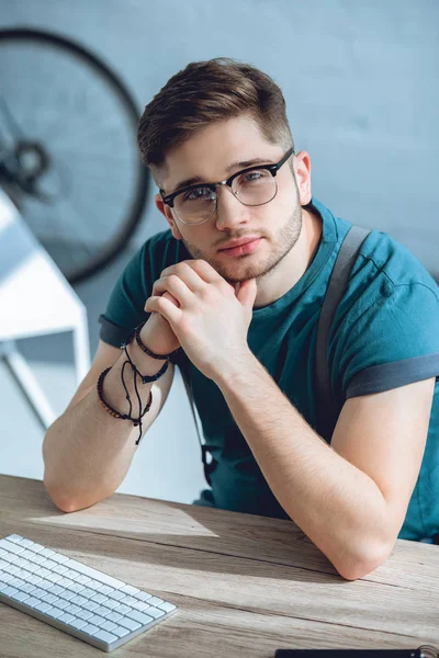 Красивий молодий чоловік в окулярах дивиться на камеру під час роботи вдома — стокове фото
