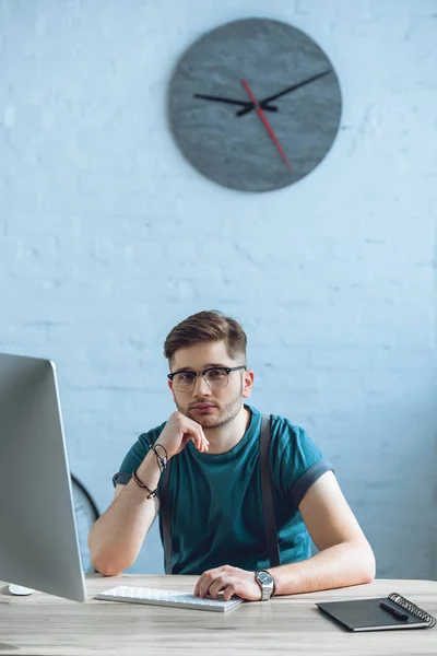 Красивый молодой фрилансер в очках за настольным компьютером в домашнем офисе — стоковое фото
