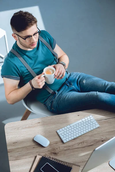 Vue grand angle de jeune pigiste boire du café et de travailler à la maison bureau — Photo de stock