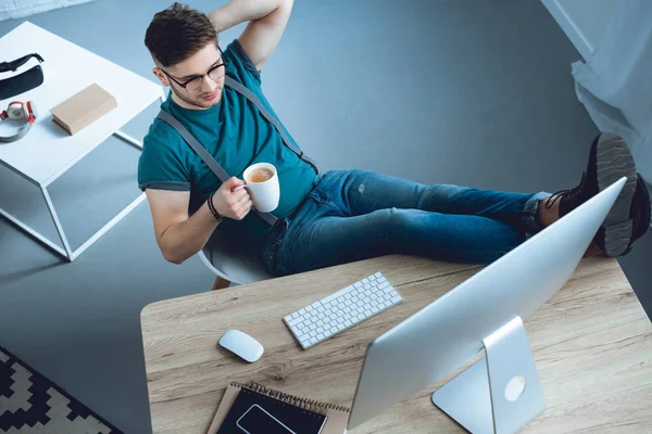 Blick aus der Vogelperspektive auf einen jungen Mann, der Kaffee trinkt und im Home Office arbeitet — Stockfoto