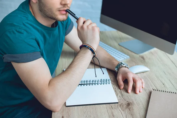 Schnappschuss eines jungen Mannes mit Stift und Notizen bei der Arbeit zu Hause — Stockfoto