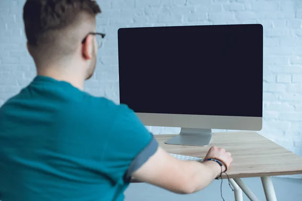 Vista trasera del hombre mirando la pantalla del ordenador en la mesa - foto de stock