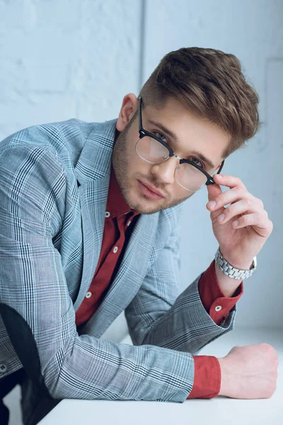 Joven barbudo con gafas elegantes apoyadas en el alféizar de la ventana - foto de stock