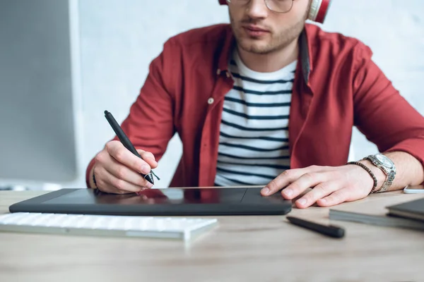 Jovem ilustrador sentado à mesa com tablet gráfico — Fotografia de Stock