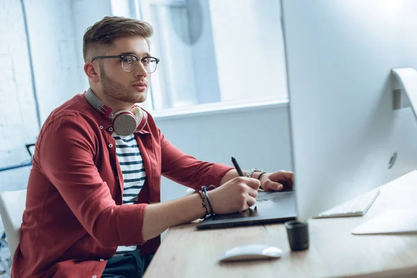 Nachdenklicher Freiberufler arbeitet am Tisch mit Grafik-Tablet — Stockfoto