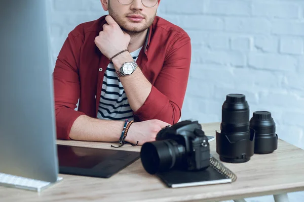 Bearded man sitting by table with camera and graphic tablet — Stock Photo