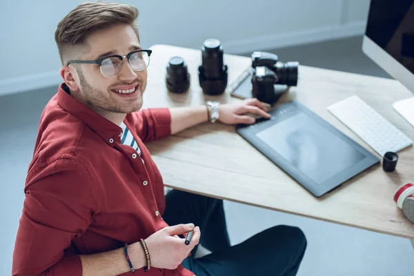 Homem freelancer feliz sentado à mesa de trabalho com tablet gráfico — Fotografia de Stock