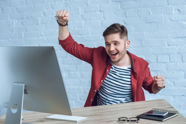 Happy freelancer man sitting by working table with computer — Stock Photo