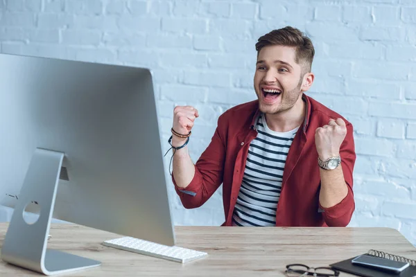 Emocionado freelancer en la mesa con pantalla de ordenador - foto de stock