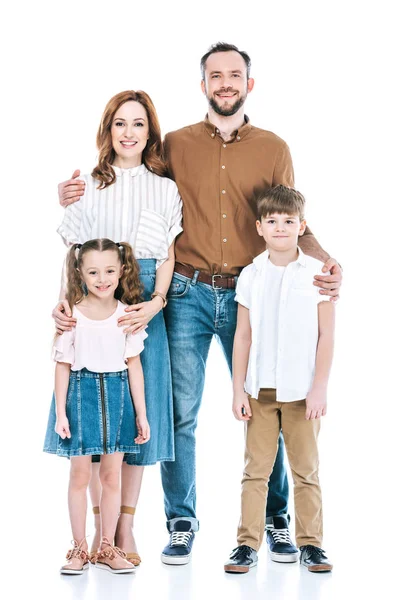 Вид в полный рост счастливой семьи с двумя детьми, стоящими вместе и улыбающимися перед камерой, изолированной на белом — стоковое фото