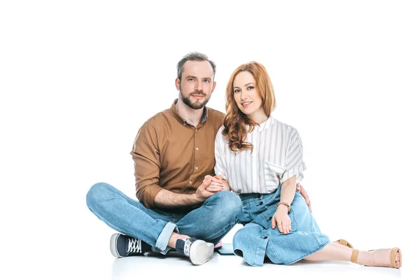 Beautiful happy couple sitting together, holding hands and smiling at camera isolated on white — Stock Photo